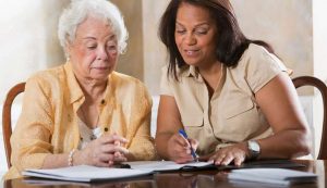 Smiling woman assisting elderly woman with paperwork